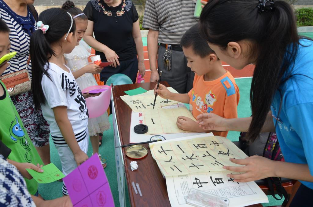游园会上志愿者带领市民体验书法魅力